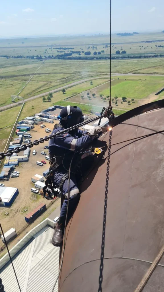 SAWA Construction 3Rope access technician performing welding work at height on a power station structure.